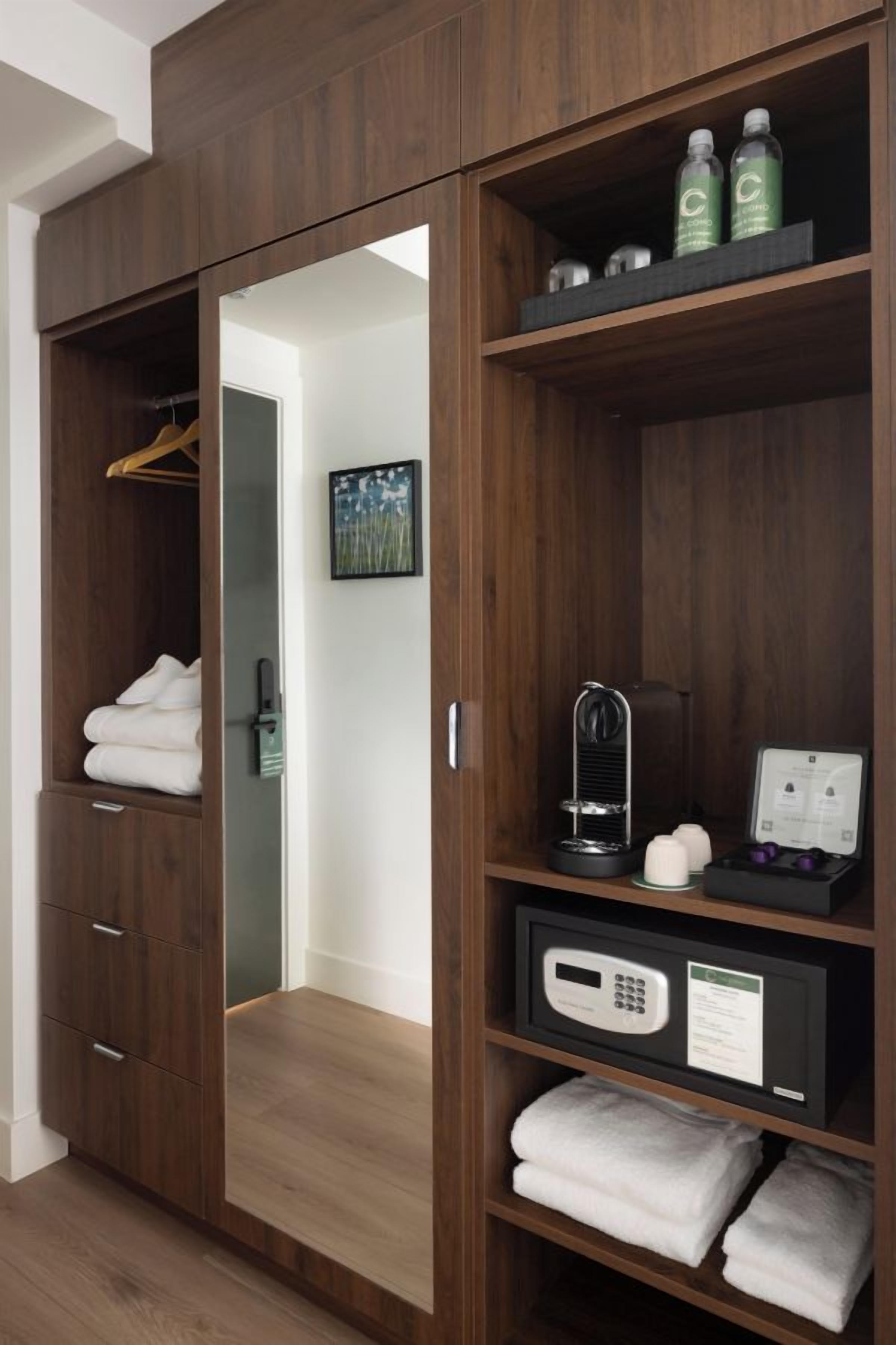 A wooden wardrobe with a mirror, a hanging rack, and shelves with toiletries and folded towels.