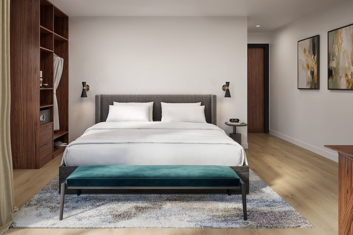 A modern bedroom with a large bed, a wooden wardrobe, a bedside table with a clock, and abstract wall art.