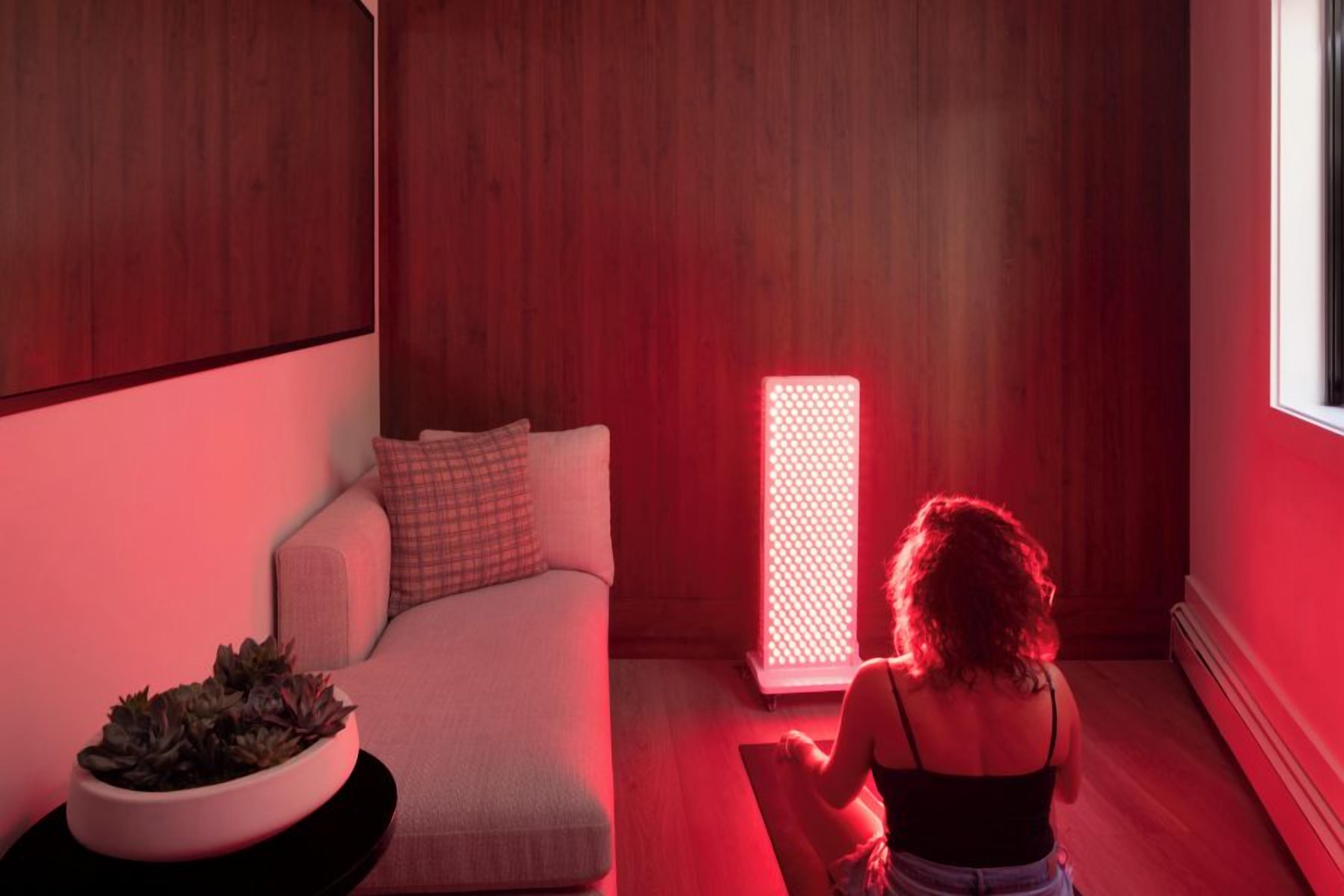A room with a white sofa, a potted plant, and a red-lit device.