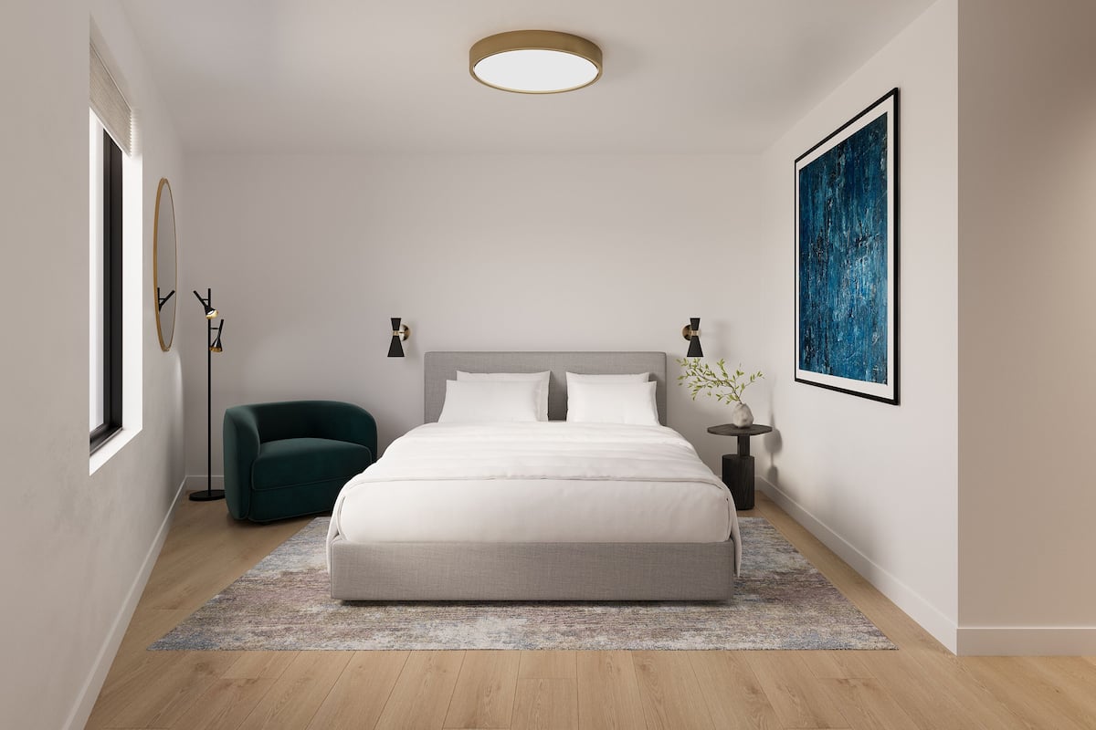 A modern bedroom with a large bed, a green armchair, a small side table, and a large abstract painting on the wall.