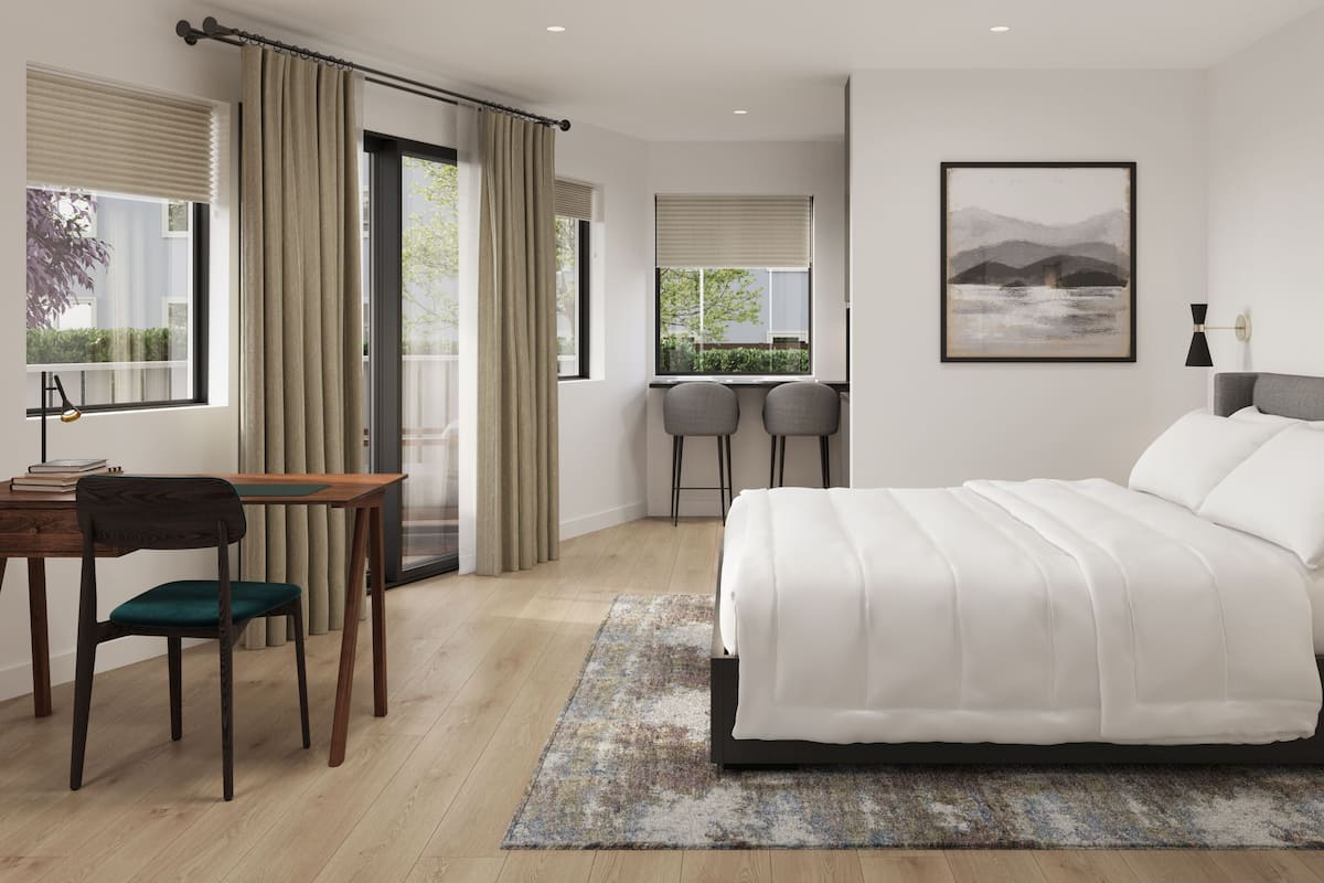 A modern bedroom with a large bed, a desk with a chair, two bar stools, a large window with curtains, and a framed picture on the wall.