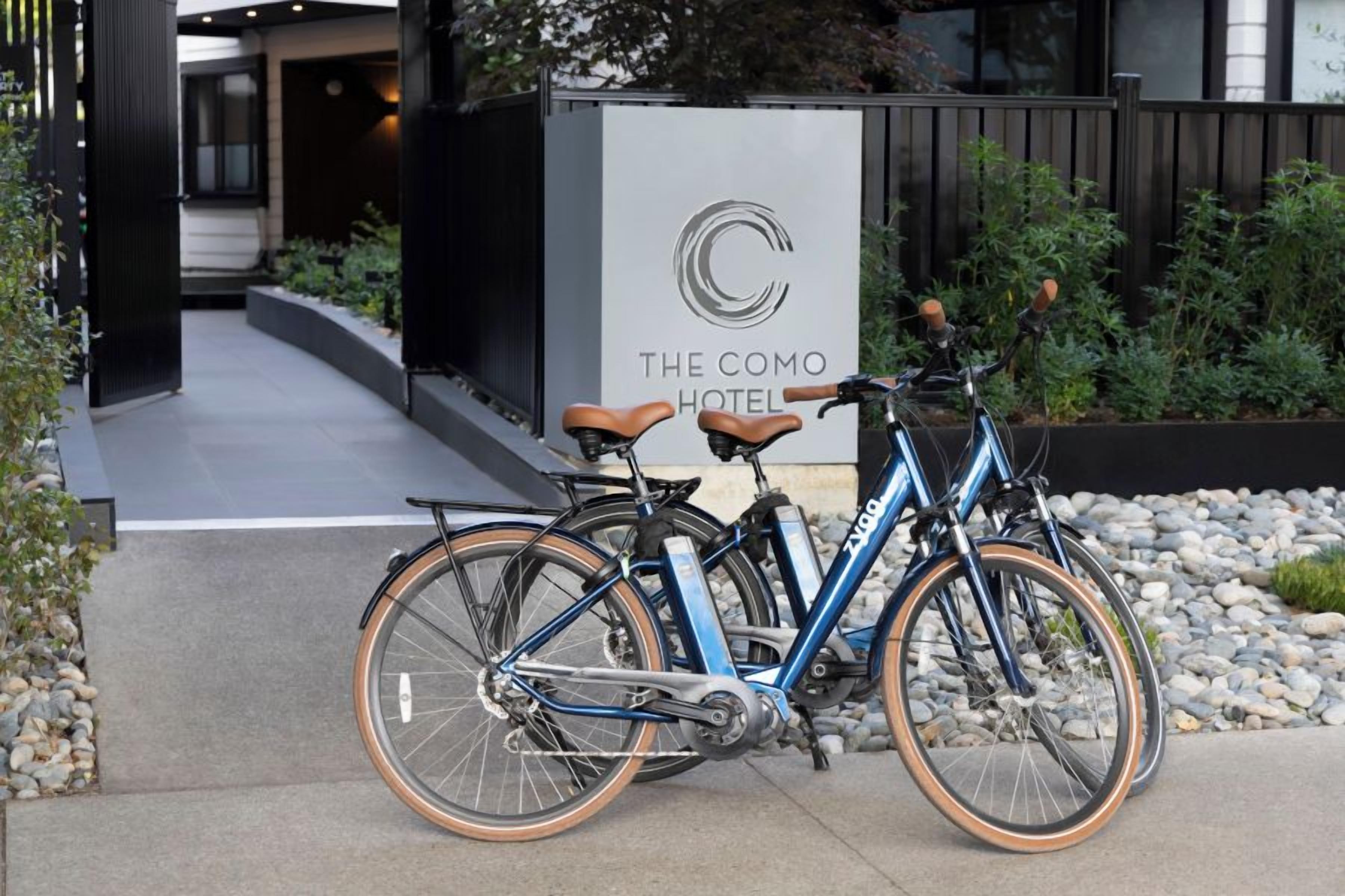 A bicycle parked in front of a hotel entrance with a sign that reads 'The COMO Hotel.'