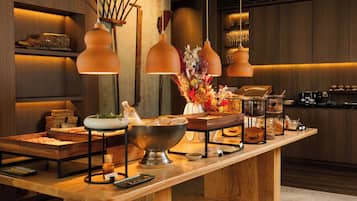 A buffet setup with a variety of food items, a large bowl, and a vase of flowers.