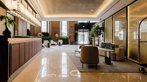 Eine moderne Lobby mit einer Rezeption, einer Sitzecke und großen Fenstern.