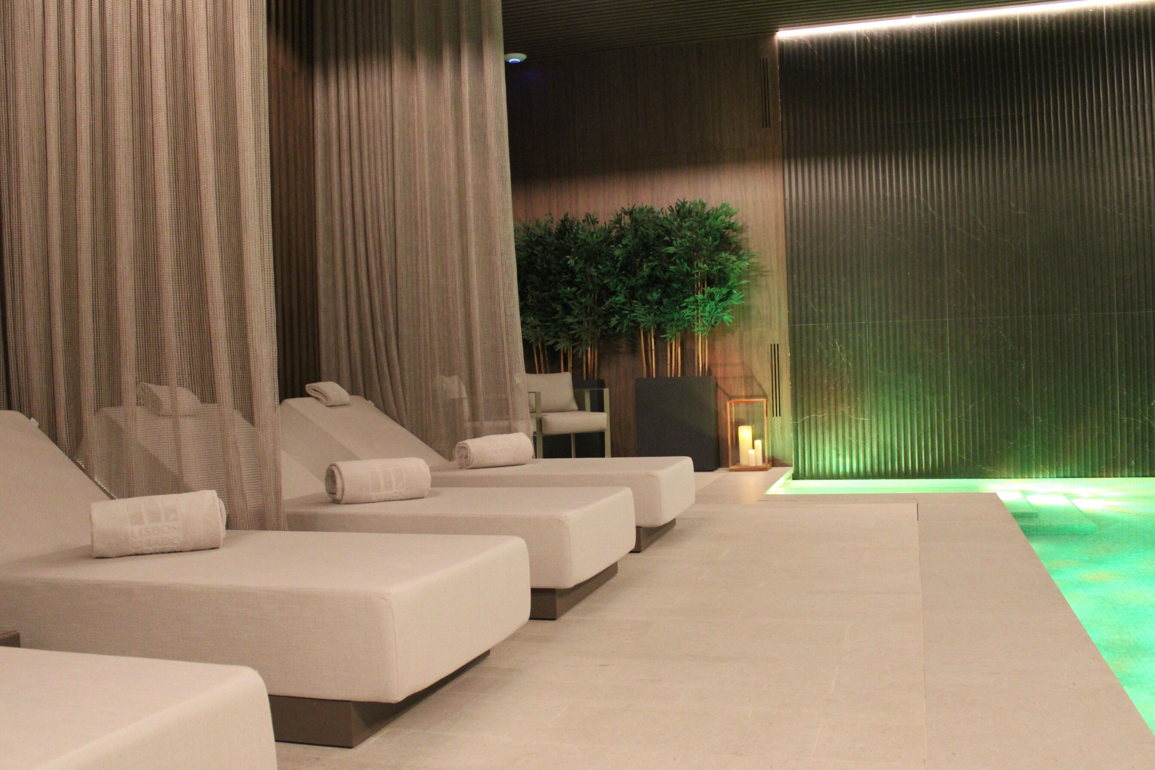 A spa area with multiple massage beds, a green plant wall, and a large textured wall.