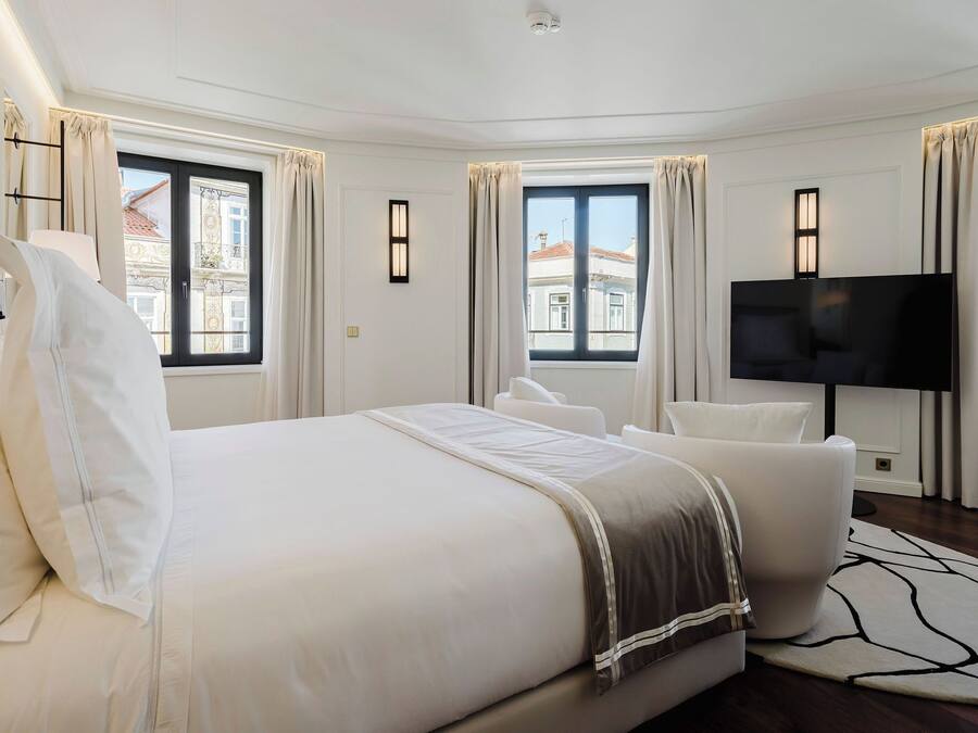 Camera d'albergo moderna con un letto grande, una TV a schermo piatto e vista sulla città attraverso le finestre.