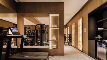 Un gimnasio moderno de hotel con una cinta de correr, máquinas de ejercicio y un quiosco digital.