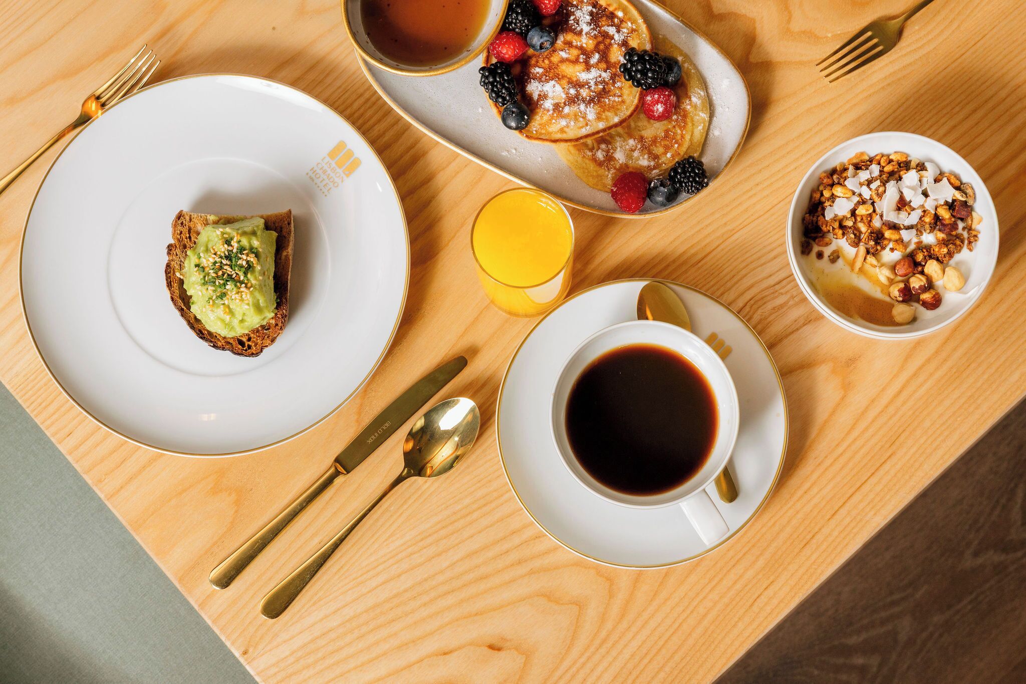 Desayuno con tortitas, bayas y una taza de café sobre una mesa de madera.