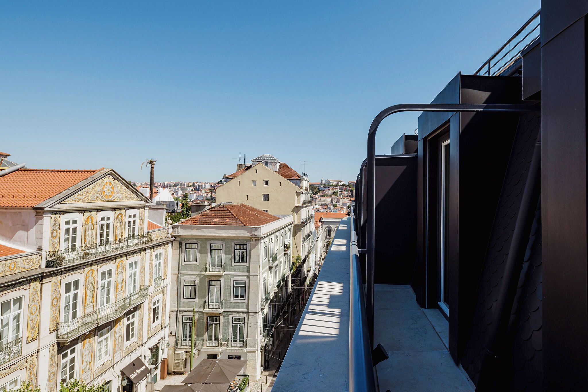 A high-rise building with balconies, a clear sky, and a view of other buildings.