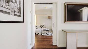 A hallway with a framed black and white photo, a white console table, and a sofa in the background.
