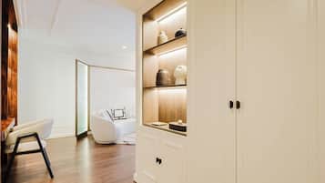 A modern interior with a wooden floor, white walls, and a white wardrobe with shelves.