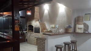 Una cocina con horno de ladrillo, un lavamanos y taburetes de bar.