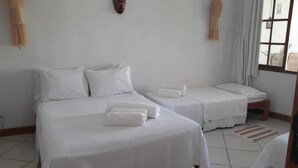 Habitación de hotel con dos camas, ropa de cama blanca y una ventana con cortinas.