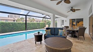A poolside area with a sofa, chairs, and a dining table. - 5* 3 BR 3 BA Home 4 min walk to beach & Marriott (Marco Island)