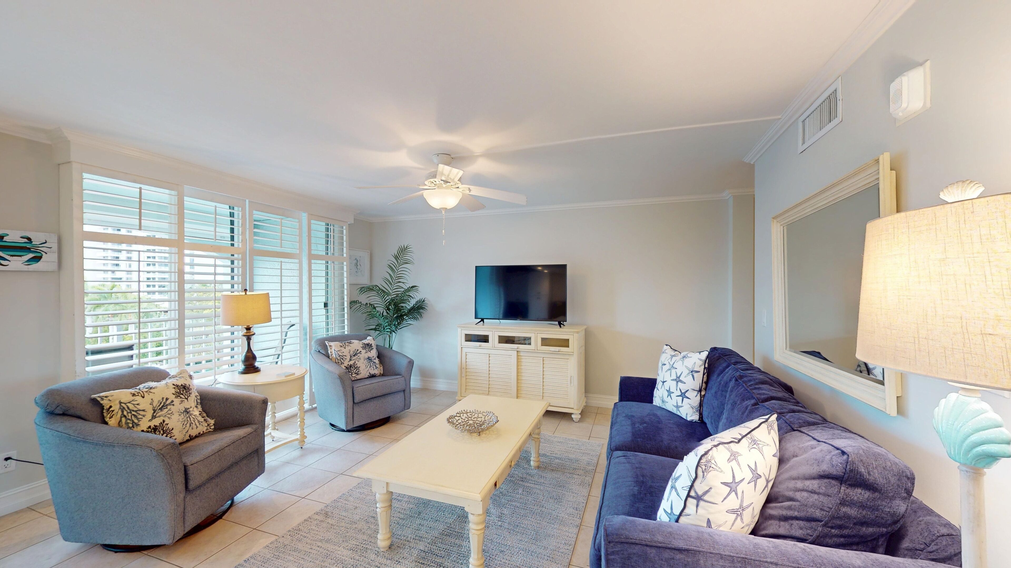 A living room with a ceiling fan, a TV on a cabinet, a sofa, a coffee table, and a lamp.