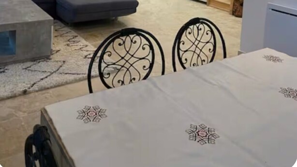 Ein Wohnzimmer mit einer Couch, einem Esstisch mit Stühlen, einer Treppe und einer Tür.