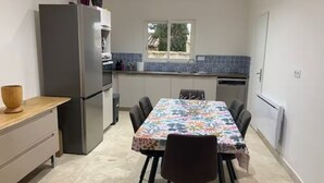 Eine kleine Küche mit Esstisch, Stühlen und einem Kühlschrank.