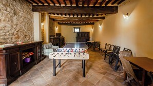 Una habitación acogedora con mesa de fútbol, muebles de madera y paredes de piedra.