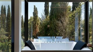 A modern bathroom with a large window, a bathtub, and a sink.