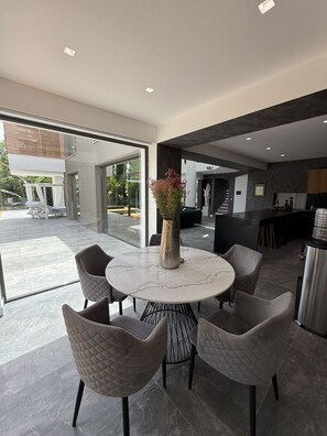 Un espace repas moderne avec une table en marbre, des chaises rembourrées et un vase de fleurs.