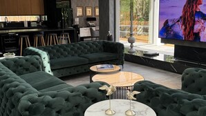 A spacious living area with a large green sofa set, a coffee table, and a television.