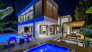 A modern house with a swimming pool, outdoor seating, and a hot tub.