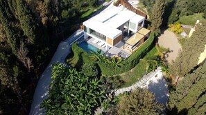 Une maison moderne dotée d’une piscine, entourée d’une végétation luxuriante et d’arbres.