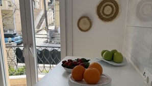 A kitchen with a white countertop, a bowl of strawberries, and a plate of green apples.