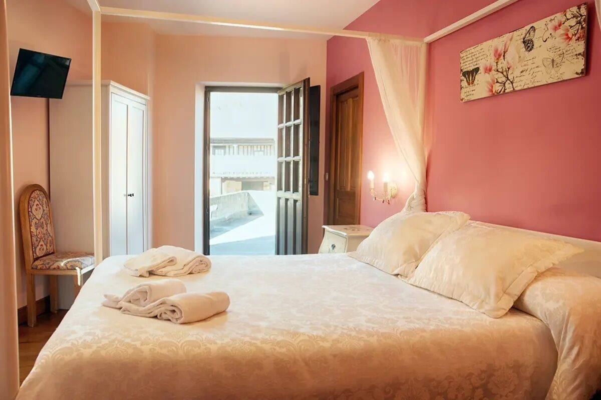 Una habitación de hotel con cama, una silla, un televisor y una puerta que da a un espacio al aire libre.