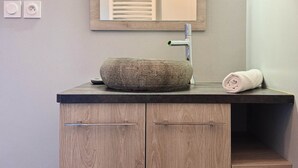Une salle de bain avec un meuble-lavabo en bois, un lavabo sur colonne et un miroir au-dessus.
