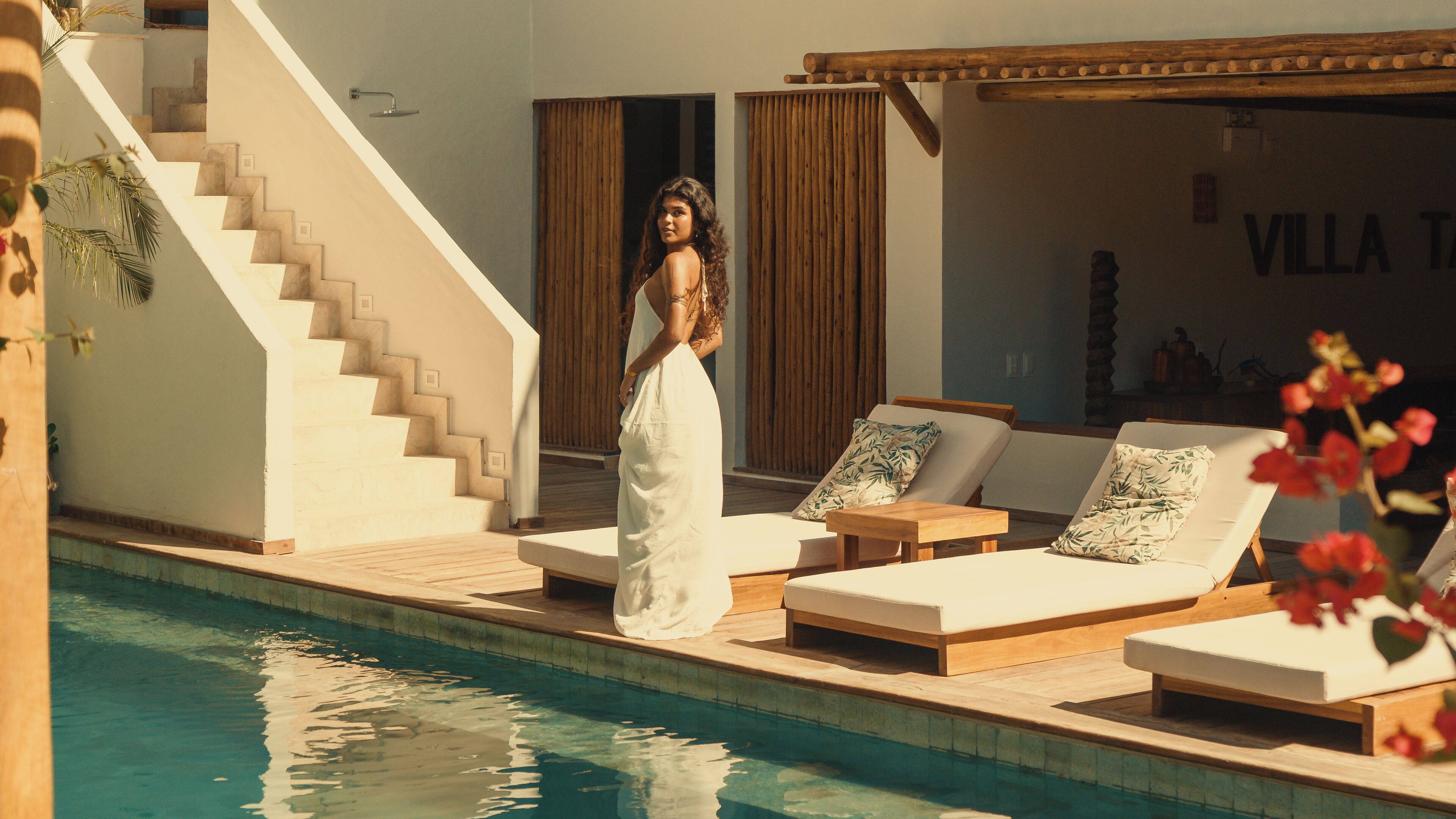 A poolside area with lounge chairs, a staircase, and a wooden pergola.