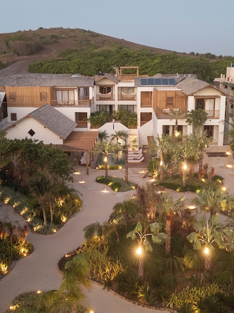 A resort with multiple-story buildings, a central courtyard with a pool, and surrounding lush greenery.