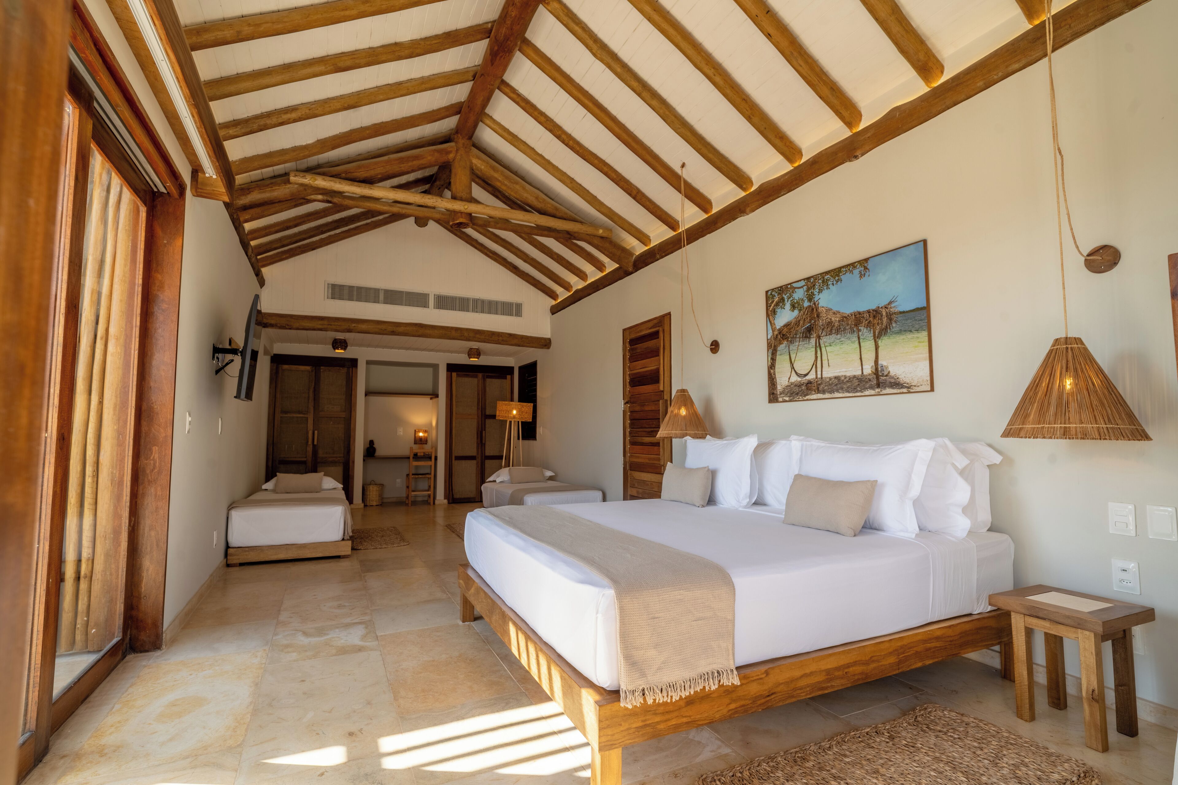 A bedroom with a large bed, wooden beams, a painting, and a lamp.