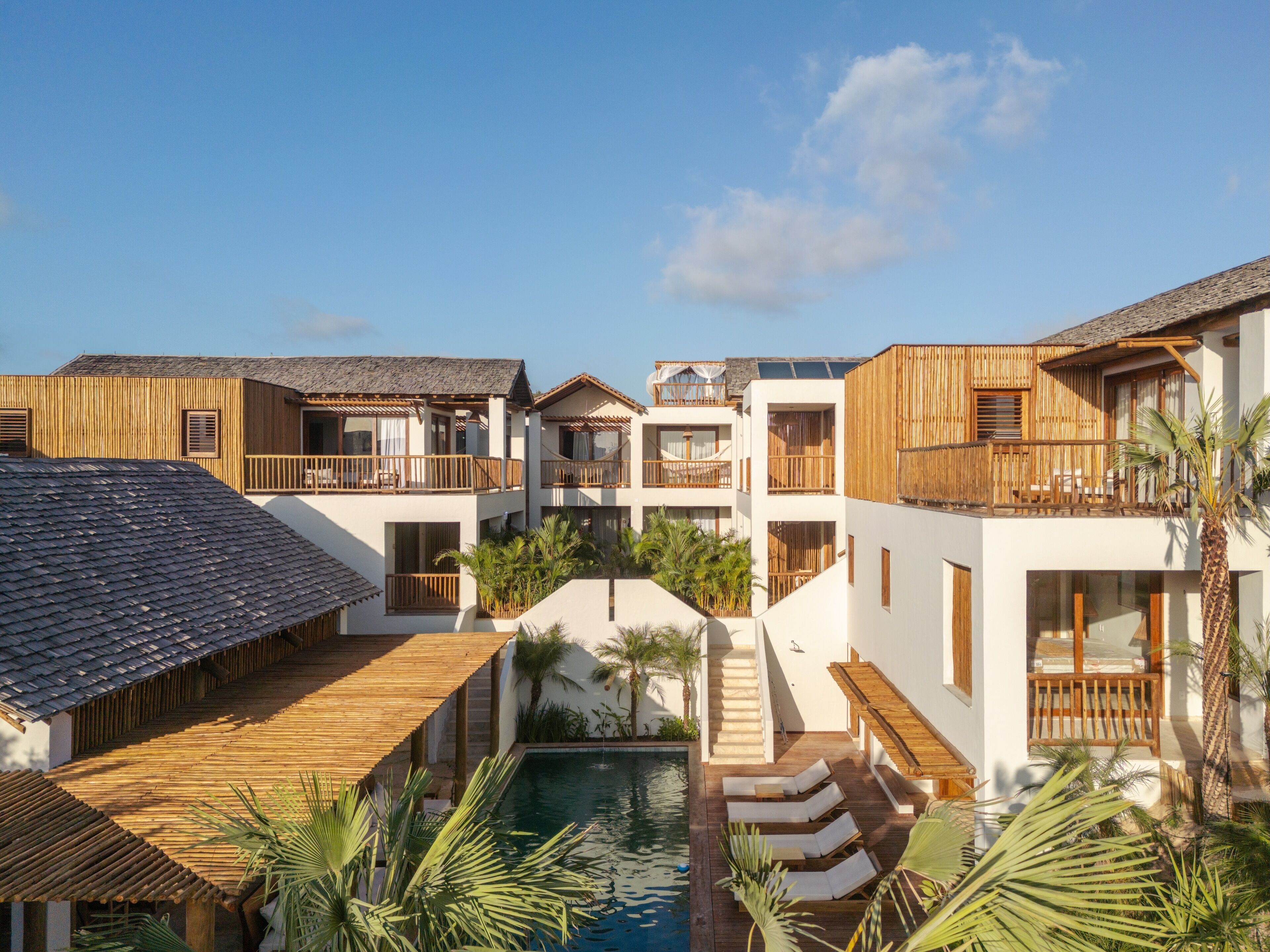A resort with multiple buildings, a central pool, and wooden deck areas.