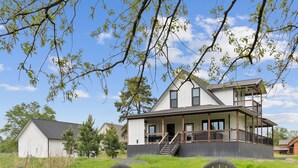 A house with a large porch and a fire pit in the foreground. - Gettin' By Cozy 2 Bedroom Cabin with Hot Tub & WiFi in Charming Broken Bow (Broken Bow)
