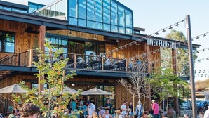 An outdoor seating area with tables and chairs, a wooden building with a glass facade, and a sign reading "HAYEN FARM TABLE". - Fox Point Farms Retreat with Ocean Views - extended stays (Encinitas)