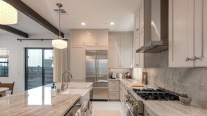 A modern kitchen with a central island, stainless steel appliances, and a large window. - Fox Point Farms Retreat with Ocean Views - extended stays (Encinitas)