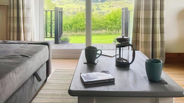 A room with a bed, a table with a book, a lantern, and a cup.