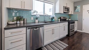A modern kitchen with white cabinets, a stainless steel dishwasher, a double oven, and a microwave. - Sf City Ocean View. Free parking inside the compound. 15 min beach Drive (Oakland)