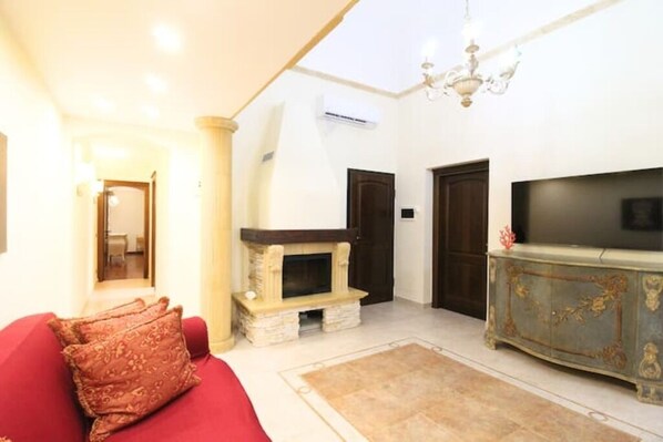 A living room with a red sofa, a fireplace, a television, and a decorative cabinet. - Elegant and cozy Apartment just minutes from the beach and downtown. (Trapani)