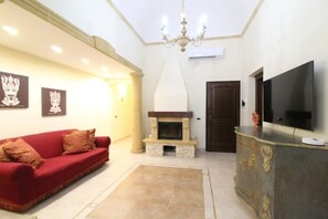 A living room with a red sofa, a fireplace, a television, and framed pictures on the wall. - Elegant and cozy Apartment just minutes from the beach and downtown. (Trapani)