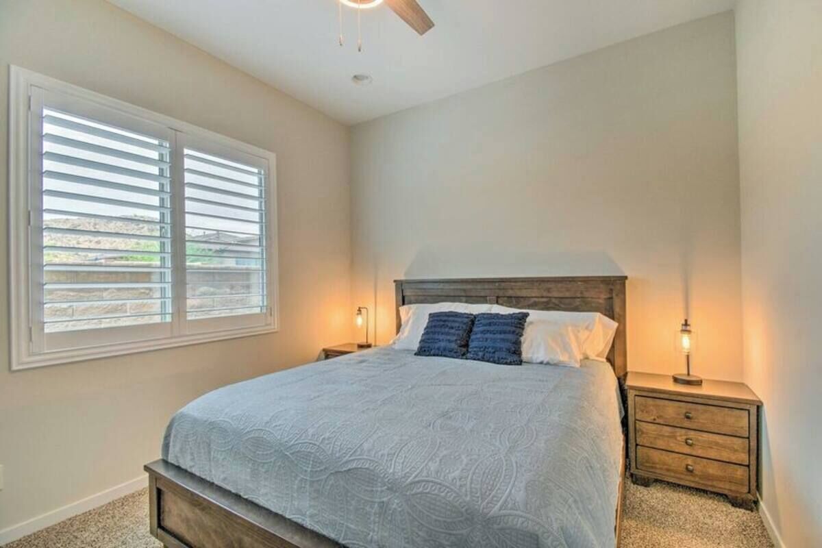 Ein Schlafzimmer mit einem Bett, zwei Nachttischen, einem Deckenventilator und einem Fenster mit Jalousien.