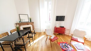 A dining area with a wooden table and chairs, a fireplace, and a television.