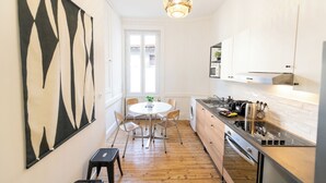 A modern kitchen with white cabinets, a stainless steel stove, and a dining area with a round table and chairs.