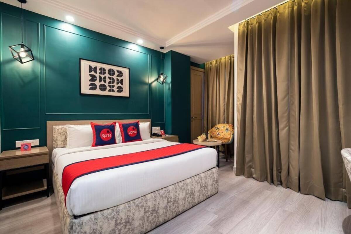 A hotel room with a large bed, a nightstand, a chair, and a window with curtains.