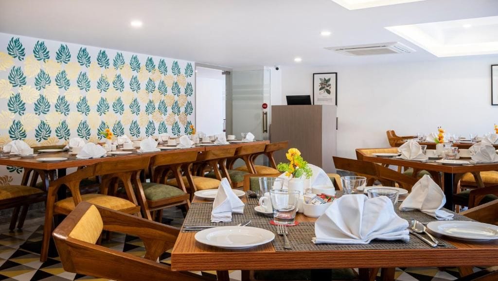 A dining area with multiple tables set for service, wooden chairs, and a patterned wall.