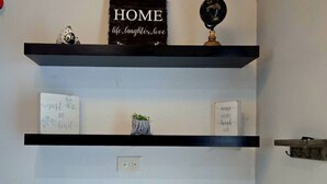 A kitchen with three black shelves, a countertop with various food items, and a small plant. - 2-bedroom condo in charming Carolina with WiFi, AC. 4 min walk to beach! (Carolina)