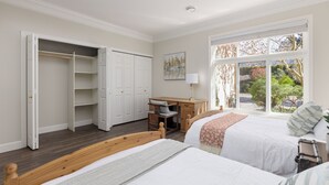 Een slaapkamer met twee bedden, een bureau en een kledingkast.