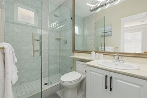 A modern bathroom with a glass-enclosed shower, a white toilet, a sink with a mirror above it, and a towel rack with a white towel. -  Family Room.  2 Double Beds.  Private Bath. Free Parking .Central AC. (Richmond)
