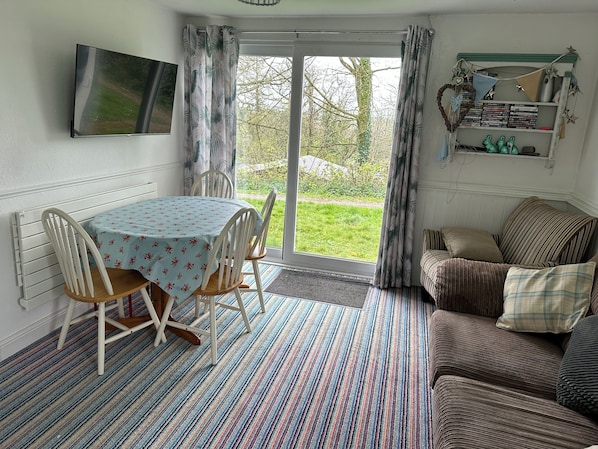 A cozy room with a dining table, chairs, a sofa, and a bookshelf.